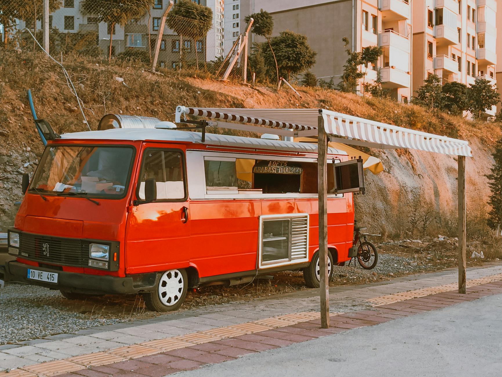 Wybieramy busa do food trucka i mobilnego punktu usługowego: modele z najlepszą zabudową Czerwony food truck zaparkowany przy ulicy w Turcji pod markizą