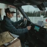 Kurier prowadzi bus dostawczy z paczkami, korzystając z nawigacji GPS