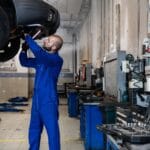 Mechanik sprawdza podniesiony samochód dostawczy w warsztacie