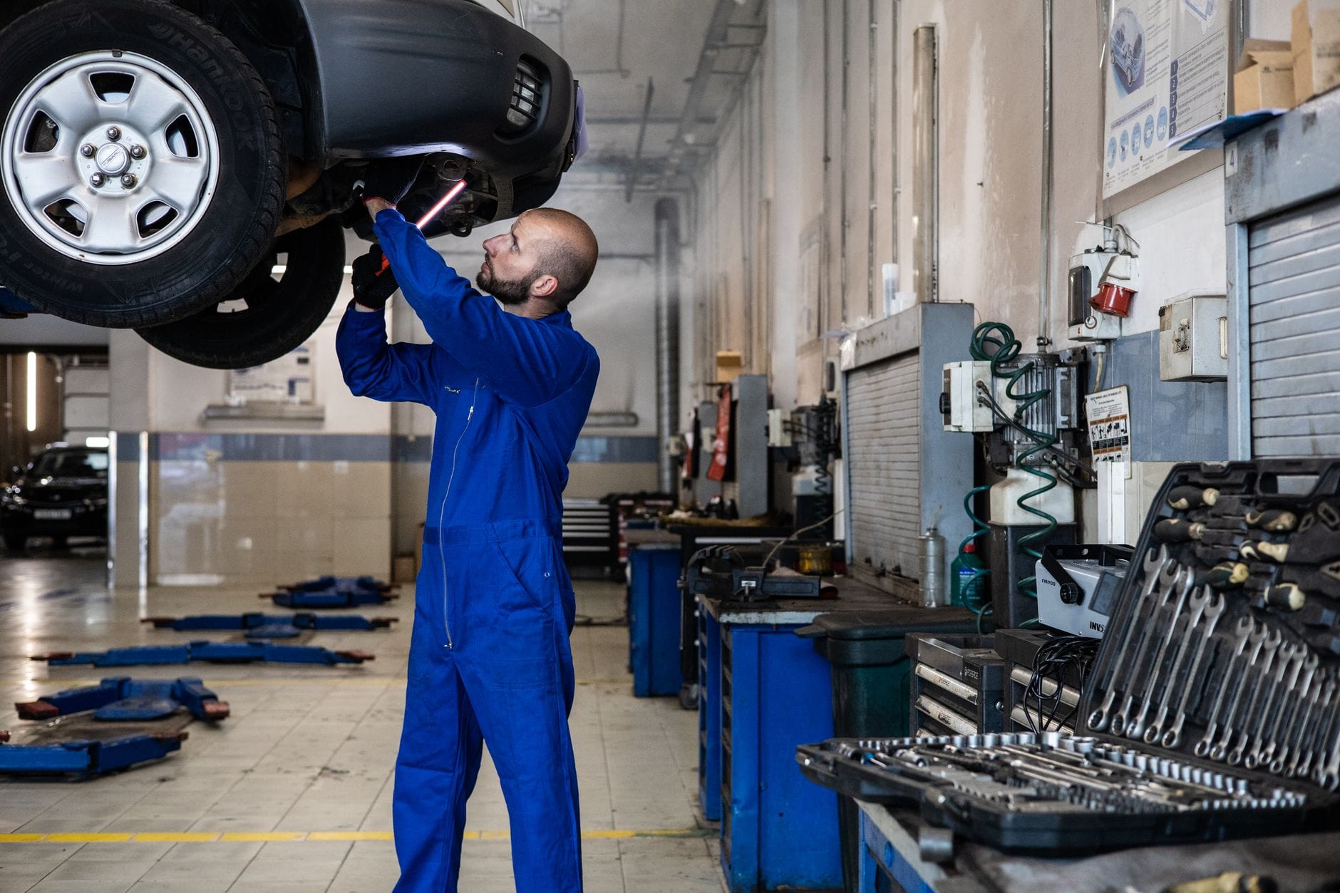 Mechanik sprawdza podniesiony samochód dostawczy w warsztacie