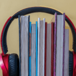 Słuchawki na stosie książek jako symbol słuchania audiobooków