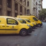 Trzy żółte auta dostawcze zaparkowane na ulicy w Barcelonie