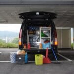 Tył czarnego busa z zabudową sprzętową na miejskim parkingu