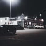 Nocny plac salonu z oświetlonymi używanymi samochodami premium