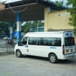 Biały minibus zaparkowany na dworcu pod metalową wiatą