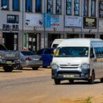 Ruchliwa ulica w mieście z samochodami i białym minibusem taxi